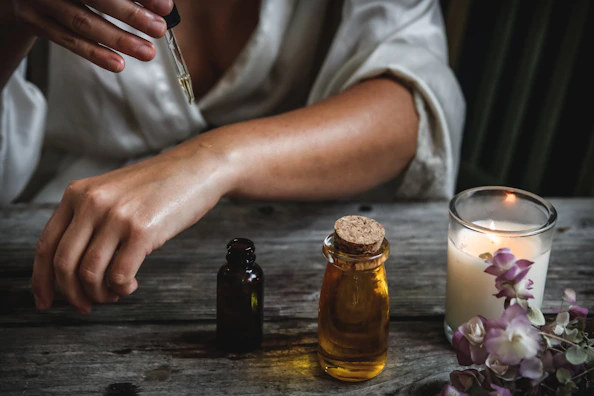 A therapist preparing aromatic oils in golden bottles for a massage.
