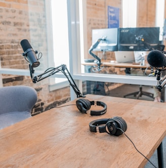 two black headphones on brown wooden table