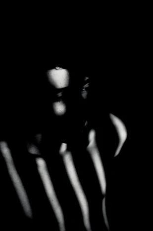 A shadowy, minimalist portrait capturing deep emotion through light and darkness.