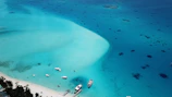 Golden hour view of a serene beach with crystal-clear turquoise water and a luxury yacht anchored nearby.