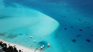 Golden hour view of a serene beach with crystal-clear turquoise water and a luxury yacht anchored nearby.