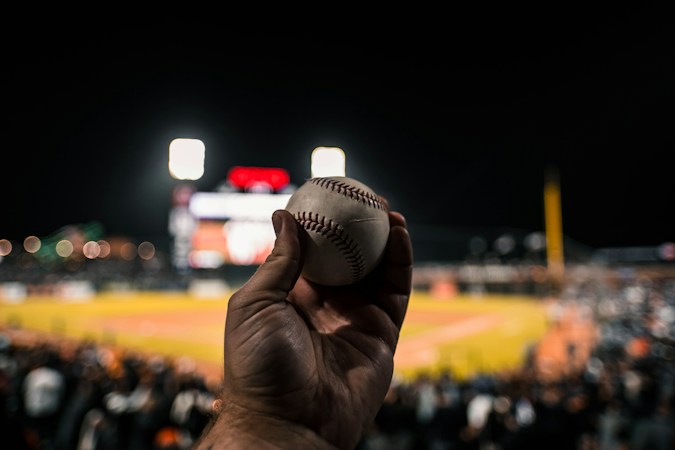 A close-up of a baseball at a stadium at night, a reminder of the UV-reactive balls used in glow-in-the-dark baseball