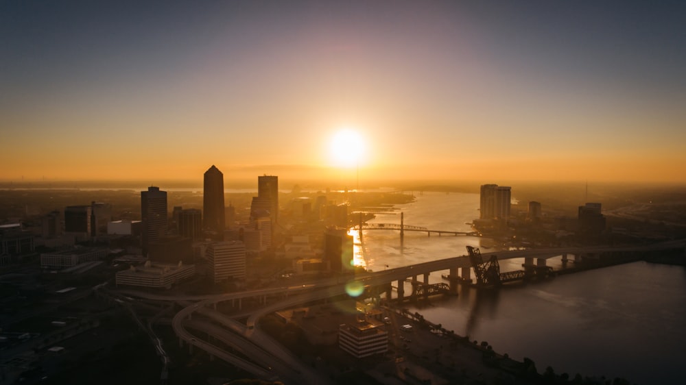 fotografia aérea da ponte e do edifício ao lado do rio durante o pôr do sol