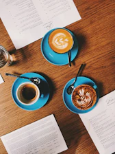 A beautifully arranged coffee menu display featuring elegant cups of espresso, lattes, and teas on a dark wooden table with warm lighting.