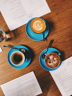 A colorful flyer design spread out on a wooden table with coffee cups nearby.