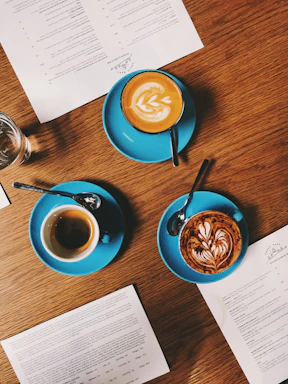 A beautifully arranged coffee menu display featuring elegant cups of espresso, lattes, and teas on a dark wooden table with warm lighting.
