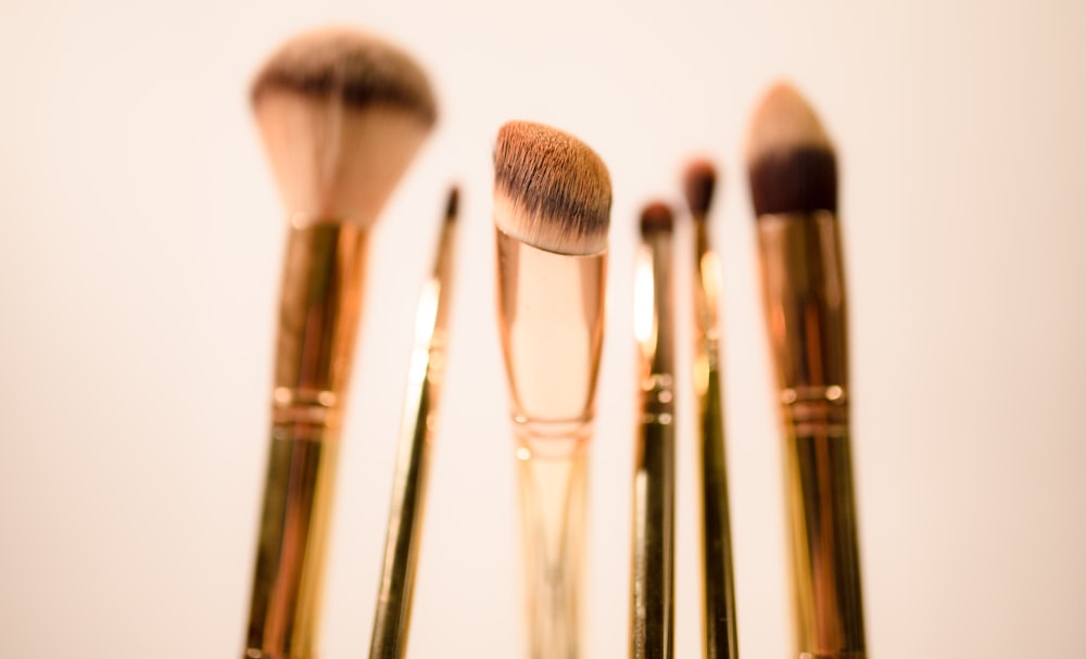 selective focus photography of gold makeup brushes