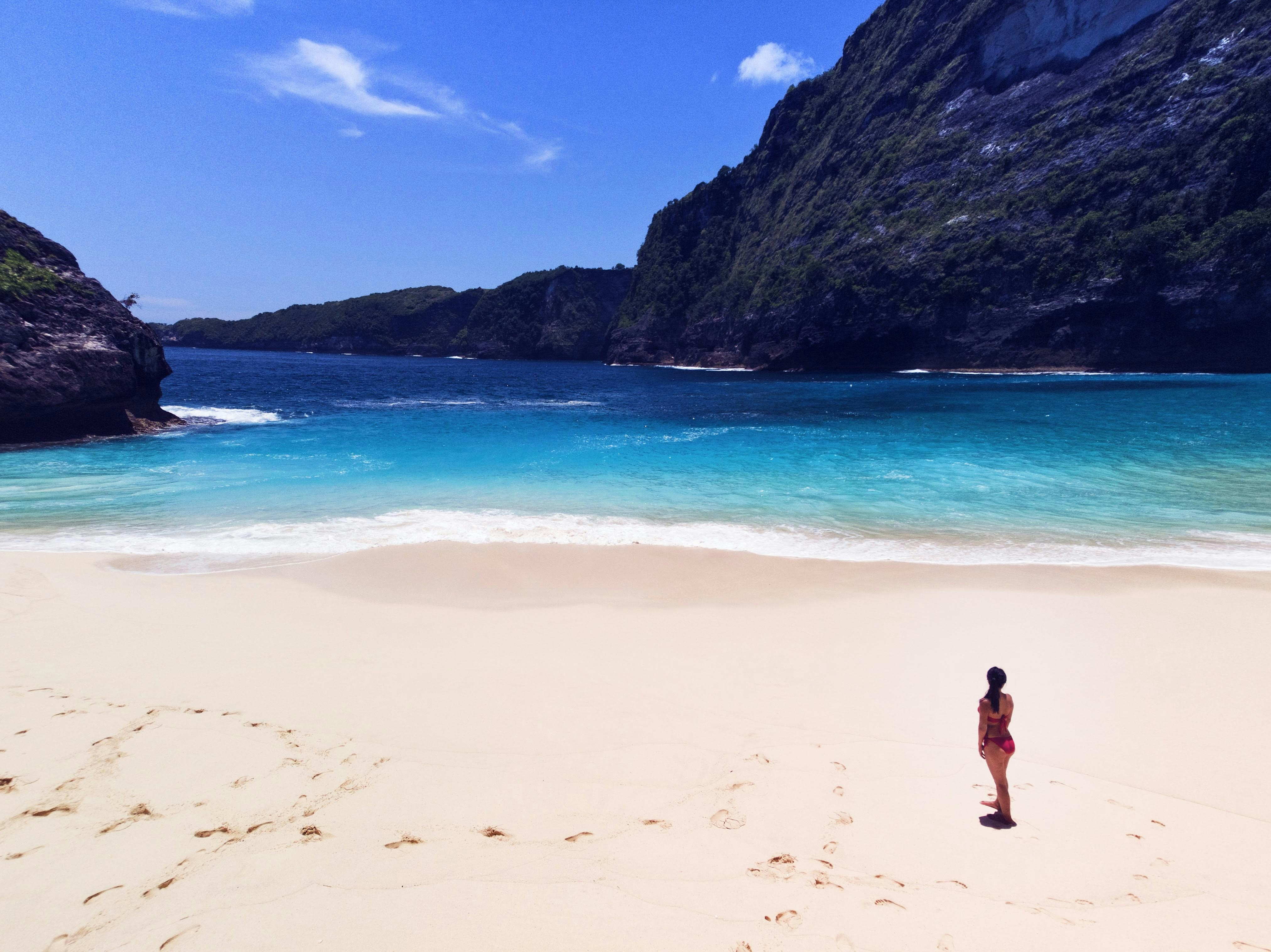 wanita berdiri di pantai di siang hari