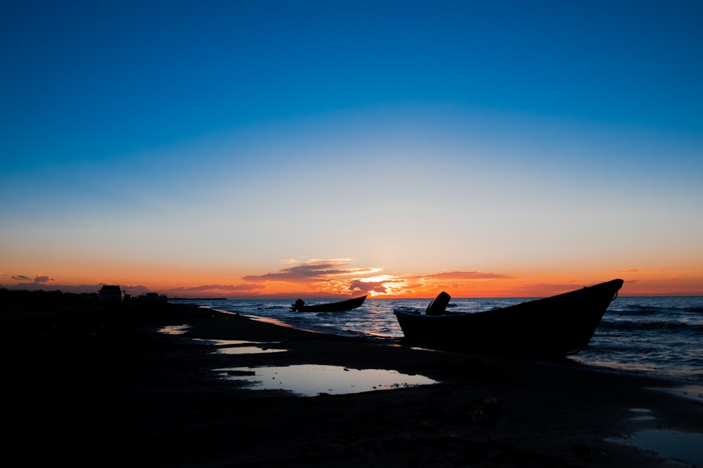 silhouette photography of boat on shore during golden hour