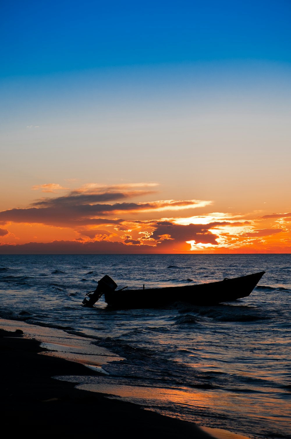 boat on beach line during golden hour