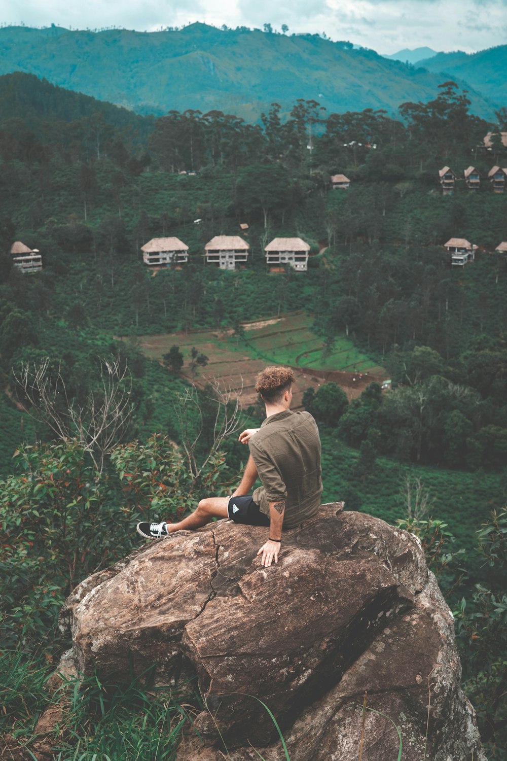 man wearing brown crew-neck shirt sitting on rock