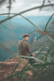 Portrait of a climber resting on a ledge, gazing thoughtfully at the landscape below.