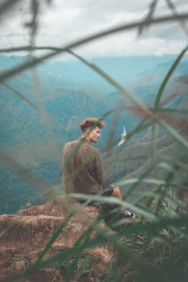 Portrait of a climber resting on a ledge, gazing thoughtfully at the landscape below.