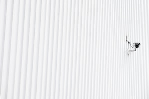 A CCTV camera mounted on a wall overlooking a secure entrance.