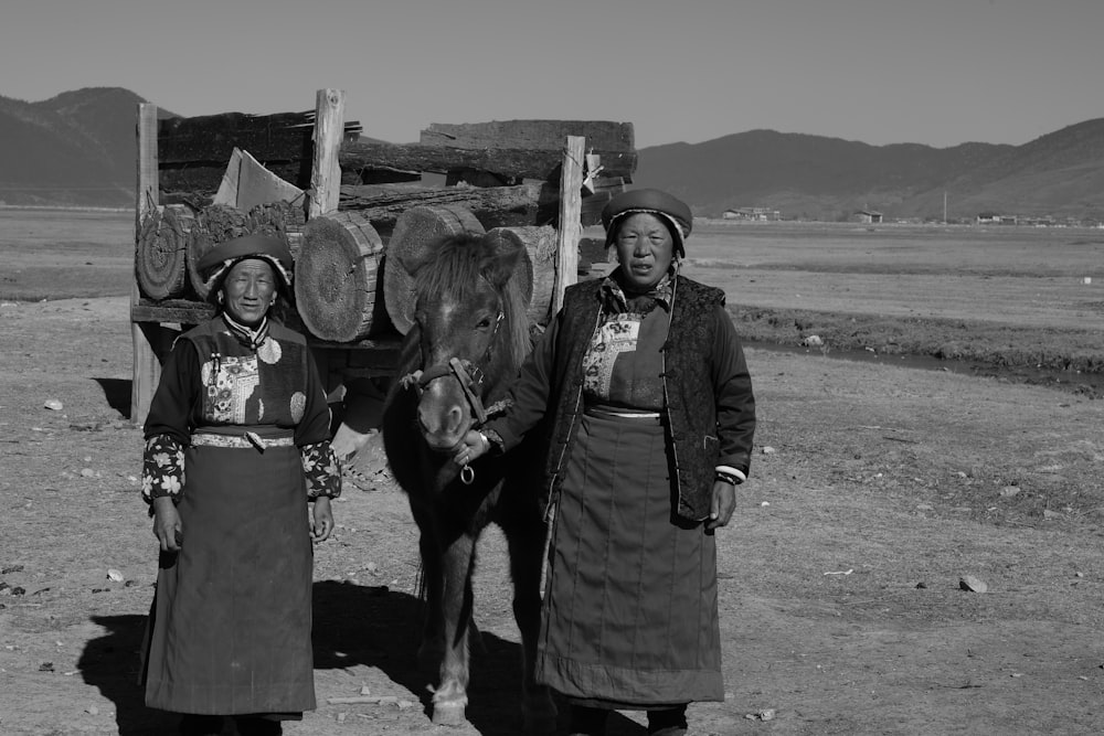 two women standing beside horse