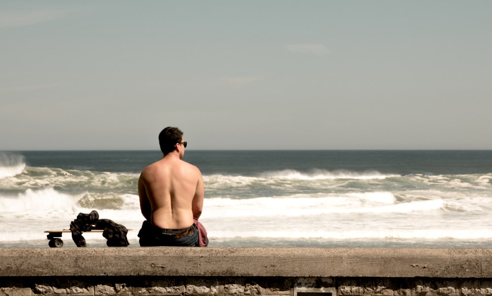 uomo seduto vicino alla spiaggia