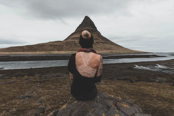 A scenic shot of a tattoo artist sketching designs outdoors with mountains in the background.