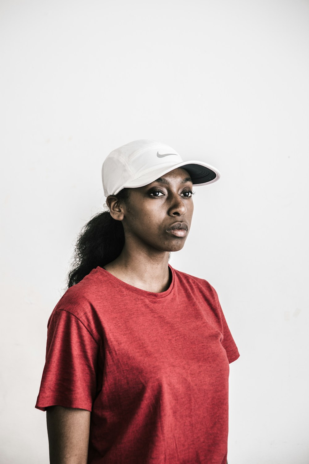 portrait of woman wearing red crew-neck shirt and white cap