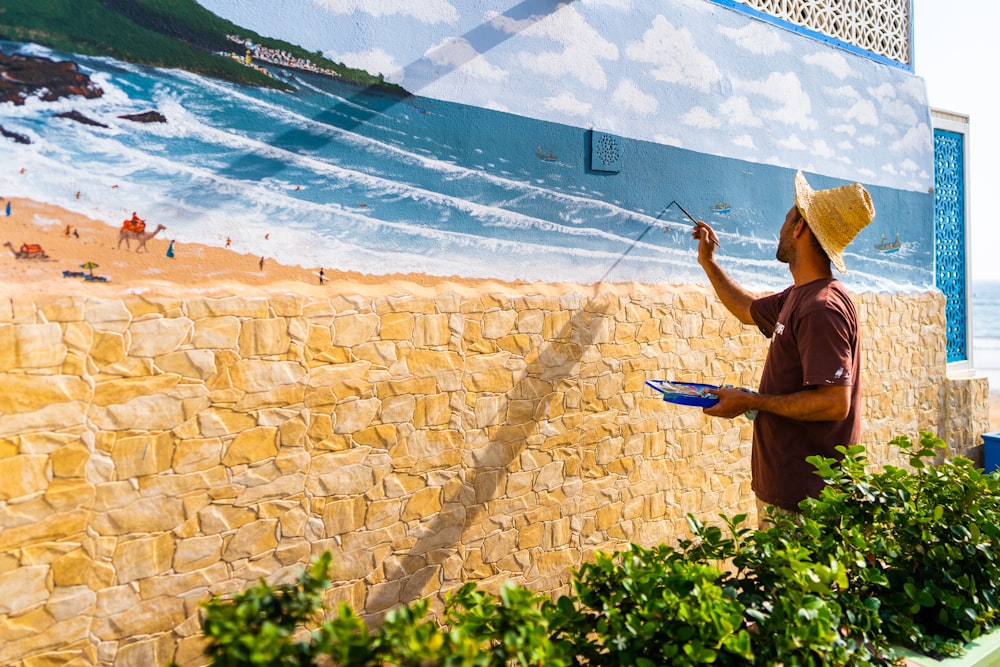 Persona con camisa negra pintando en la pared durante el día