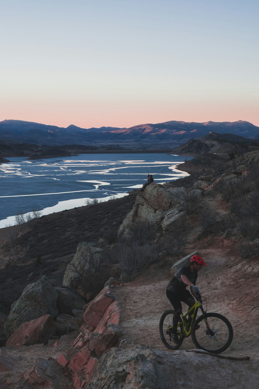 man biking on rocky hill viewing sea