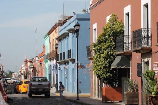 An urban street scene with people walking and colorful buildings.