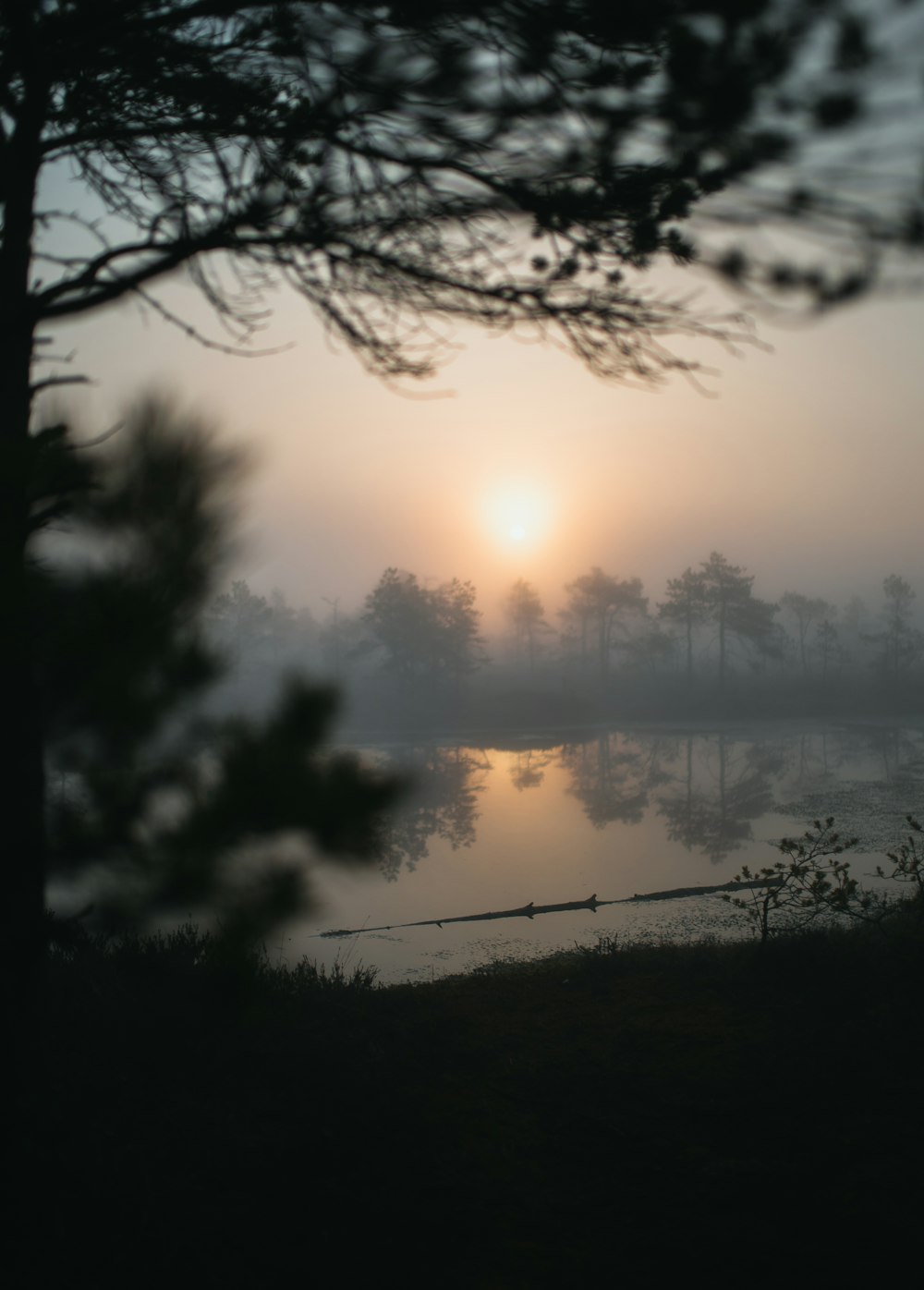 orange setting sun over foggy lake