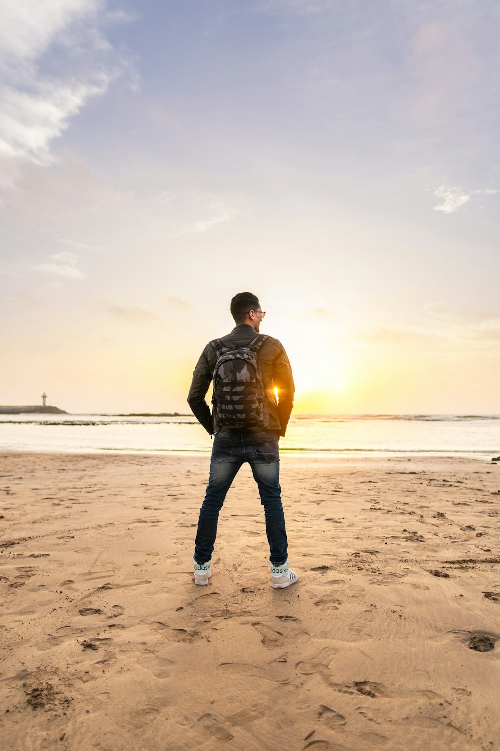 man wearing backpack standing on shore during daytime