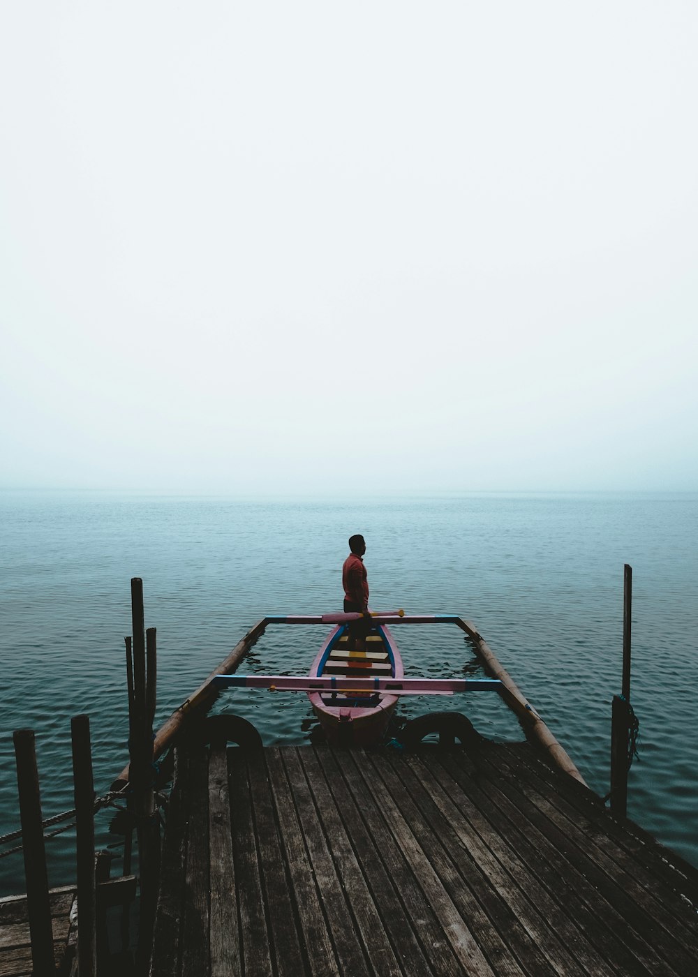 man standing in boat moored in dock