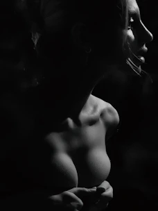 A striking fashion portrait of a model in a minimalist studio with dramatic lighting.