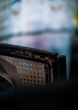 Close-up photo of an old armchair showing faded upholstery and visible tears.