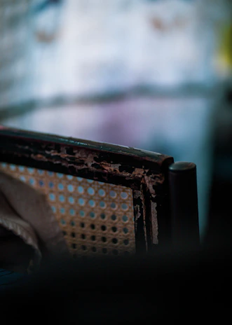 Close-up of a weathered wooden chair with soft sunlight highlighting its worn edges.