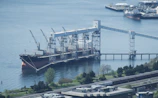 Participants interacting with a port operations expert beside a docked cargo ship.