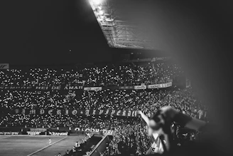 A dynamic snapshot of a thrilling football match under stadium lights, capturing the energy of the crowd and players in motion.