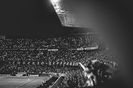 A dynamic snapshot of a thrilling football match under stadium lights, capturing the energy of the crowd and players in motion.