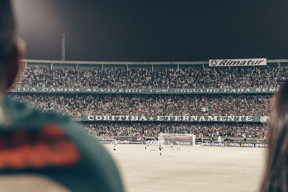 men playing soccer game surrounded with people watching