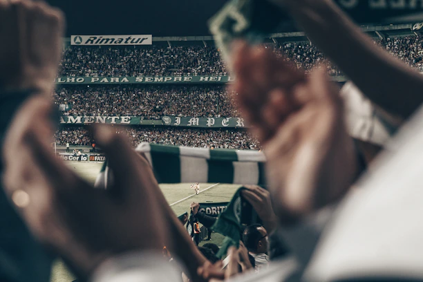 Close-up of excited fans holding tickets with the vibearena logo at a sports event.