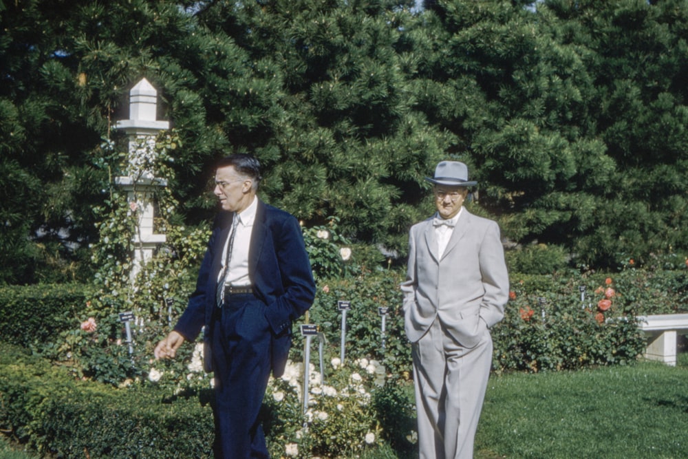 two men walking near flowers