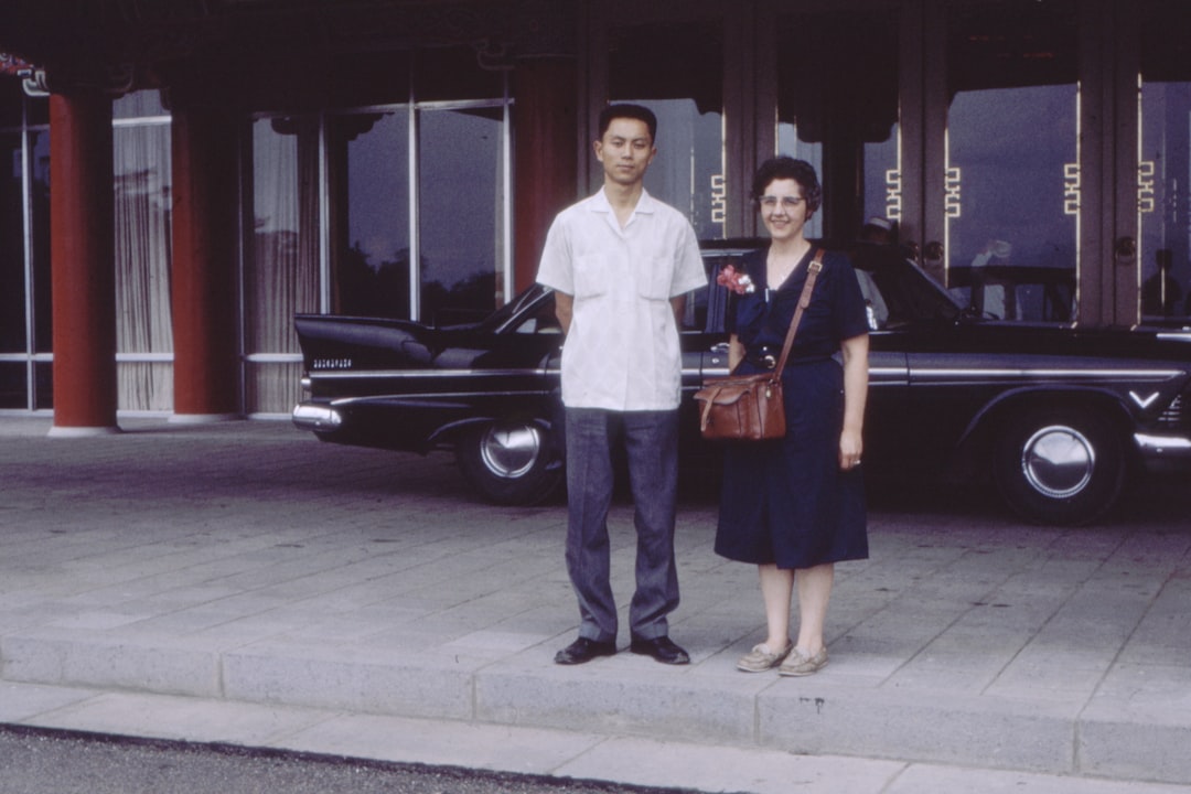 man standing next to woman near parked sedan