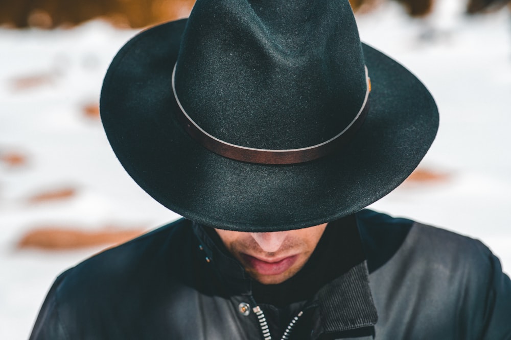 man wearing black jacket and hat looking down