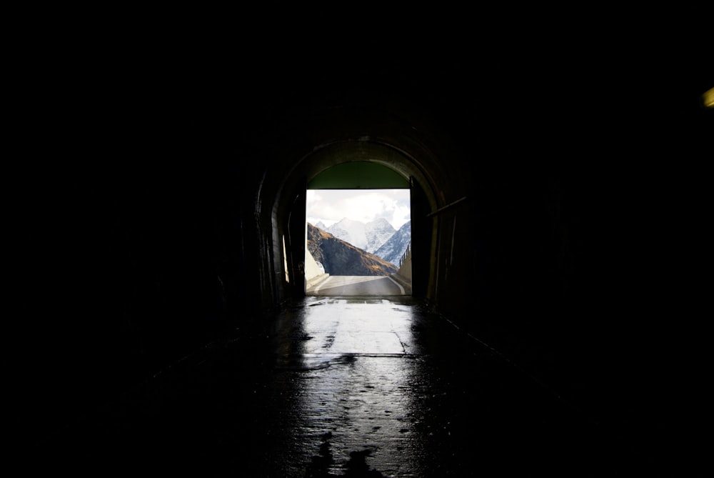 a dark tunnel with a view of a mountain