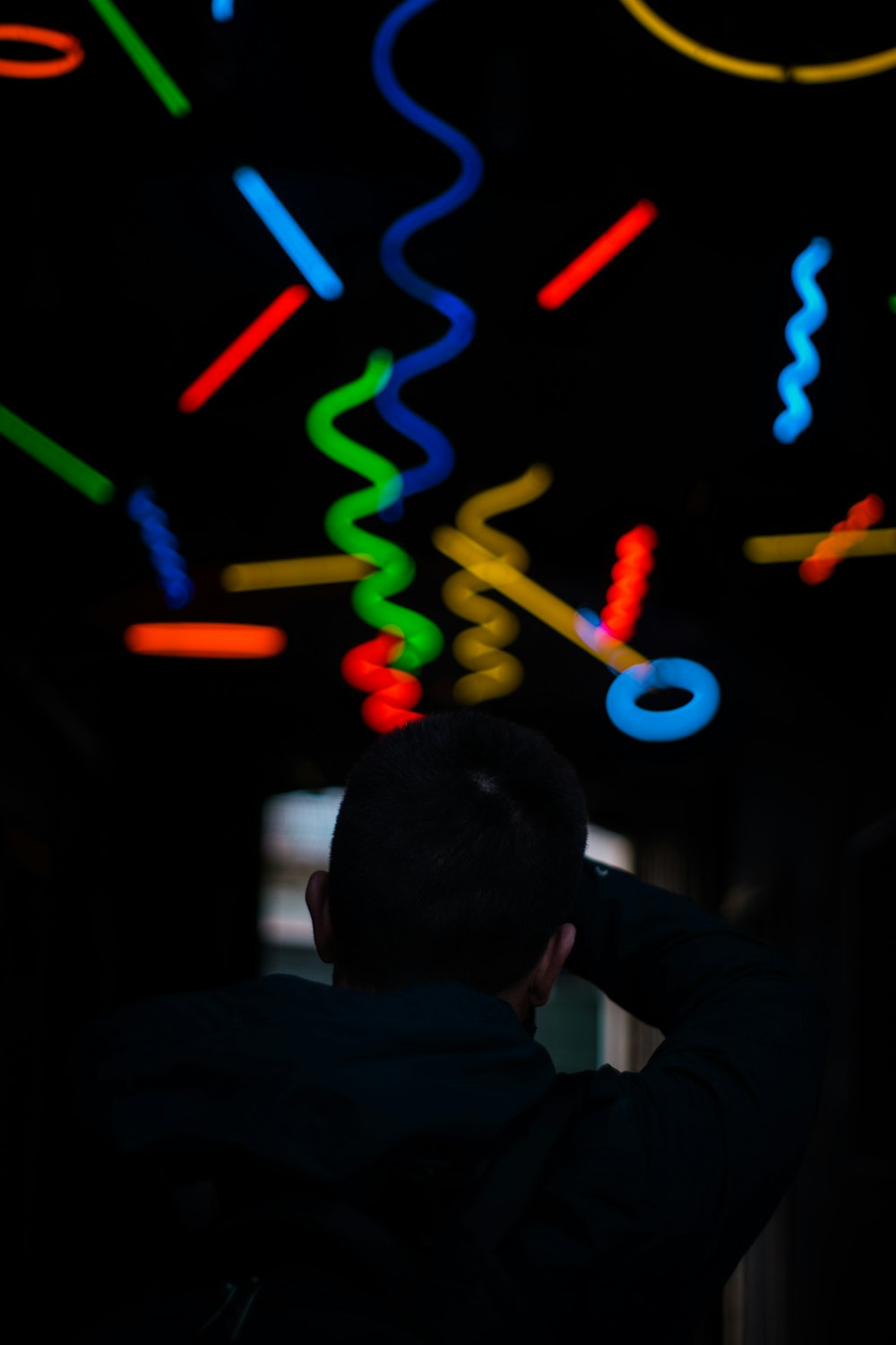 a man standing in front of a wall covered in neon lights