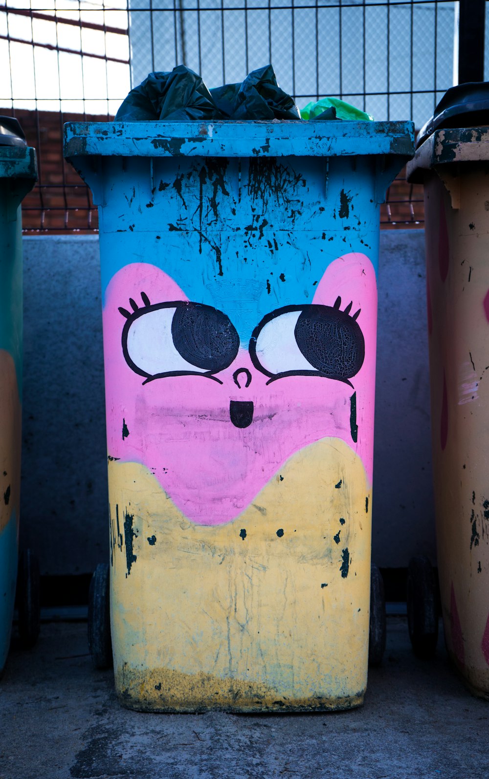 blue, pink, and yellow face print trash bin