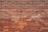 A neatly arranged pattern of red and orange brickwork forms a solid wall. The bricks are uniform in size and are laid in an even, horizontal arrangement with visible mortar lines.