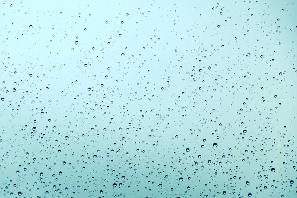 青い空を背景に窓に雨が降る