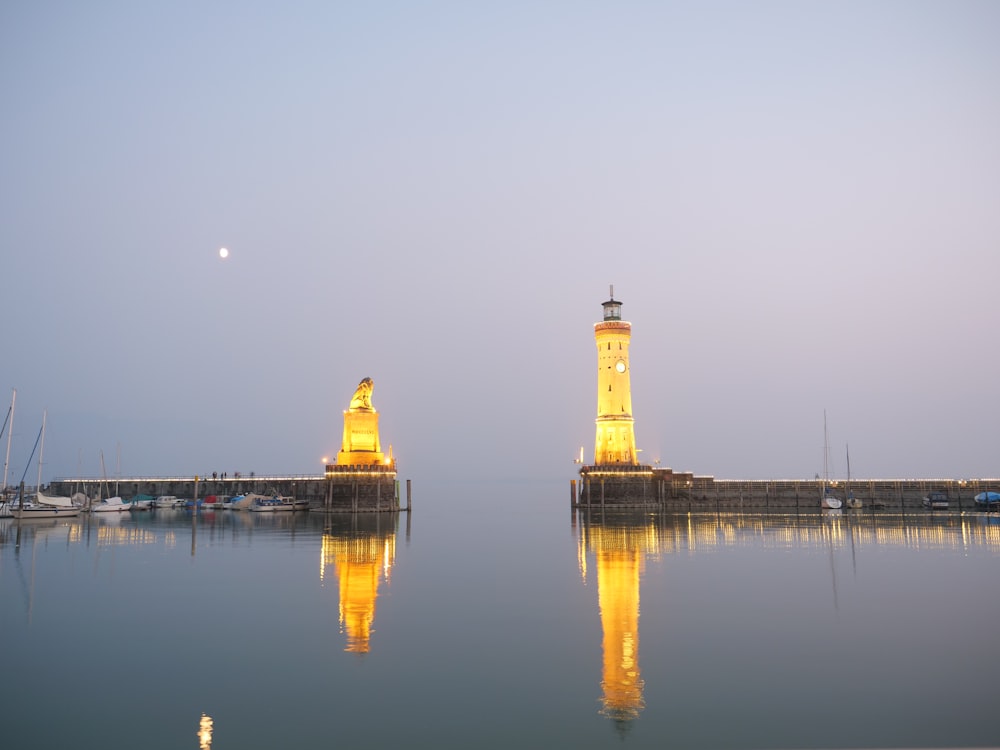 yellow lighted lighthouse and buddha statue at the bay