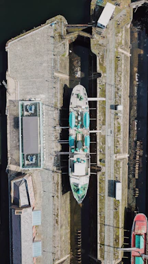 A ship docked in a drydock facility with workers inspecting the hull