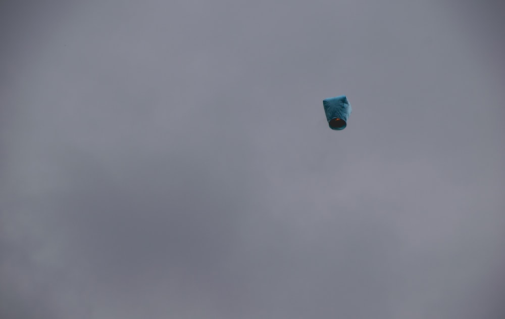 a blue kite flying in a cloudy sky