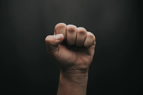 A dark, intense image of a clenched fist glowing faintly red against a black background, symbolizing inner strength and discipline.