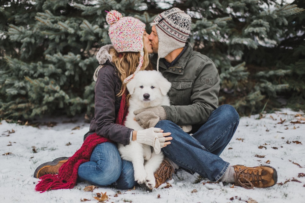 long-coated white dog between man and woman kissing