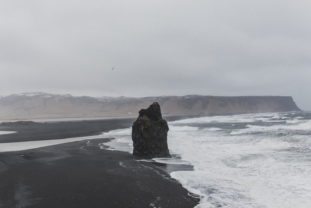 black stone formation on seashore during daytime